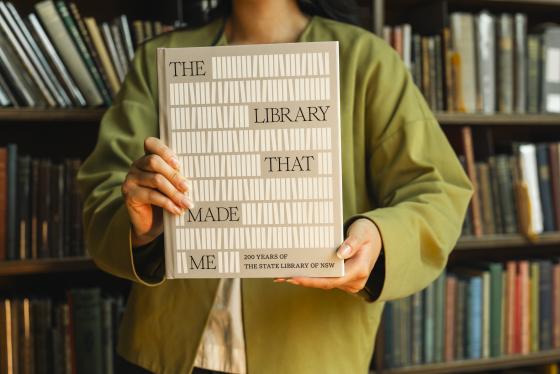 A person holding a book entitled "The library that made me"